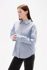 Camisa de algodón con diseño de rayas verticales finas en tonos neutros, corte holgado, cuello camisero y cierre frontal con botones.