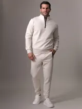 Buzo color crema de Calvin Klein confeccionado en mezcla de algodón y poliéster. Presenta cuello alto con media cremallera negra, puños y dobladillo con punto canalé.