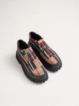 Mocasines Mutma modelo Loto, con diseño a cuadros escoceses en tonos beige, negro, blanco y rojo. Poseen suela alta tipo plataforma tractorada de color negro y detalles de elásticos laterales invisibles.