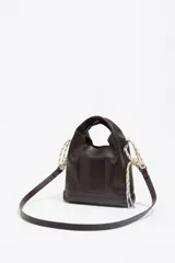 Bolso tipo bucket de cuero negro con asa de mano, tiras decorativas laterales y el logo impreso en plateado en el frente.
