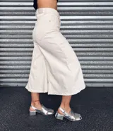 Pantalón capri color crudo, de tiro alto, pierna ancha y largo midi.