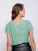 Top de mangas cortas con estampado geométrico en tonos verde y amarillo, con transparencias y costuras a la vista.