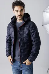 Campera de nylon termosellada con capucha, color azul marino, con cierre frontal y detalles en color naranja en el borde del cierre y costuras de la capucha.