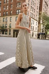 Vestido midi de cuello halter anudado, escote en pico y espalda descubierta, con diseño a rayas verticales y bajo abullonado con elástico interior.