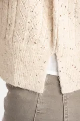 Chaleco de punto con textura trenzada, color beige melange, de cuello redondo y corte al cuerpo.