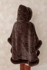 Capa de piel sintética en color negro, con diseño holgado, capucha integrada y bordes con textura de pelo largo.