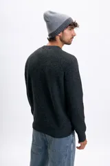 Buzo de punto de color gris oscuro, con cuello redondo y mangas largas con costuras raglán. Presenta un tejido acanalado y corte clásico.