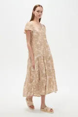 Vestido largo de viscosa con escote en V, mangas cortas y diseño amplio de faldón escalonado con estampado botánico en tonos beige y crudo.