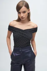 Top off-the-shoulder confeccionado en microtul con apliques brillantes. Presenta un diseño cruzado en el frente y ajuste al cuerpo.
