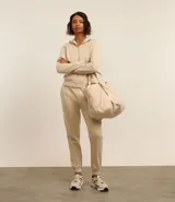 Campera deportiva color beige con cierre frontal de cremallera, capucha ajustable con cordones, mangas largas y bolsillos frontales tipo canguro. Confeccionada en tejido de algodón y poliéster.