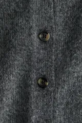 Saco de punto suave con cuello camisero, cierre frontal de botones y mangas cortas. Presenta terminaciones acanaladas en mangas y ruedo.