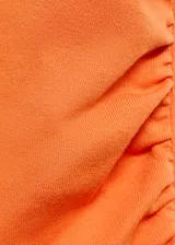 Vestido midi de color naranja, con cuello perkins y diseño sin mangas. Presenta un corte entallado al cuerpo con detalle drapeado en uno de los laterales de la cintura.