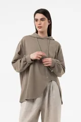 Buzo oversize color taupe con capucha, mangas voluminosas y diseño asimétrico más largo en la espalda.