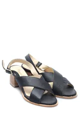 Sandalia baja de cuero negro con fajas cruzadas, hebilla lateral y taco de madera.