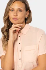 Camisa de lino de manga corta con cuello camisero, cierre frontal de medio botón con botones metálicos personalizados y dos bolsillos en el pecho.