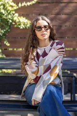Sweater tejido de algodón con diseño de rombos multicolor en tonos marrones, azul y rojo. Presenta una silueta oversize, cuello redondo y mangas largas abullonadas con puños ajustados.