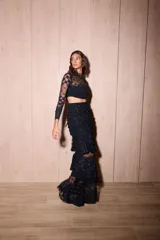 Falda larga de encaje color negro, de silueta ajustada con volados escalonados y abertura lateral pronunciada.