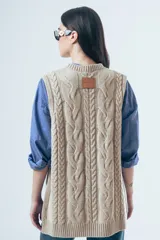 Chaleco de punto color marrón con diseño de ochos, cuello redondo y lazos laterales ajustables.