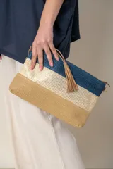 Sobre de mano de rafia con diseño de franjas horizontales en color beige, blanco y azul. Incluye lazo de mano y correa para colgar.