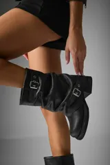 Botas de caña media color negro, confeccionadas en cuero vegano, con hebillas metálicas y suela track.