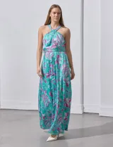Vestido largo de gasa con estampado floral en tonos turquesa, rosa y verde. Tiene cuello halter cruzado, corte en la cintura con faja plisada y abertura en la espalda con cierre invisible.
