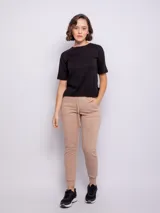 Pantalón tipo babucha de corte deportivo, color beige, con cintura elástica ajustable mediante cordón, puños en los tobillos y bolsillos frontales.