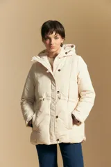 Campera acolchada de nylon en color crema, con capucha ajustable, cierre frontal con botones y cordón de ajuste en la cintura.