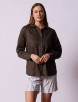 Camisa color verde oliva de lyocell, marca Cyrus. Tiene cuello con solapa, abertura central con botones, mangas 3/4 regulables con presilla y botón, y dos bolsillos delanteros aplicados.