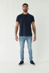 Remera polo negra de manga corta con ajuste regular. Presenta cuello y puños con ribete a rayas en gris y bordó. El logo de la marca está estampado en el pecho.