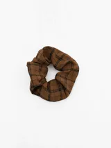Colita de pelo tipo scrunchie con diseño de cuadros escoceses en tonos marrón y negro.