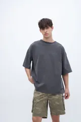 Remera de algodón con calce oversize y textura suave. Presenta un diseño de cuello redondo, mangas cortas con bordado detallado en una de ellas y un acabado de tela lavada.