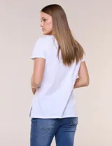 Remera de silueta recta confeccionada en algodón y elastano, de color blanco. Presenta escote redondo, mangas cortas, ruedo recto con tajos laterales y un diseño destacado en la pechera con aplique de piedras a tono.