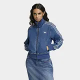 Campera Adidas modelo Firebird confeccionada en tejido denim de algodón. Presenta cierre frontal de cremallera, cuello alto, puños y ruedo en tejido rib elástico. Incluye las icónicas tres franjas en las mangas y el logo del trébol bordado en el pecho.