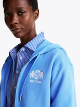 Buzo con capucha celeste de Tommy Hilfiger, con cierre de cremallera, bolsillos tipo canguro, puños y bajo de punto canalé. Logo de Tommy Hilfiger bordado en el pecho y en el ribete de la manga.