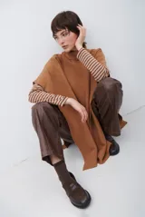 Poncho de tejido de punto color caramelo con cuello alto y diseño holgado sin mangas.