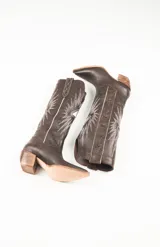 Botas texanas de cuero color marrón con bordados blancos en forma de estrellas y rayos.