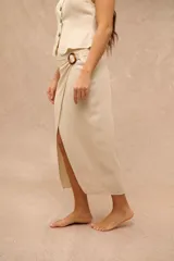 Falda midi beige tipo pareo con diseño cruzado y argolla lateral decorativa.