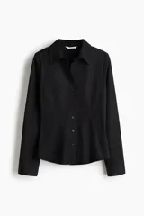 Camisa entallada negra de tejido elástico, con cuello abierto y cierre frontal de botones. Cuenta con mangas largas con puños anchos abotonados, además de pinzas delanteras y traseras para estilizar la figura.