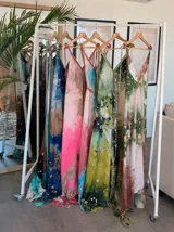 Vestido largo verde con diseño estampado tipo tie-dye y detalles dorados, de corte fluido, un solo hombro y diseño amplio.