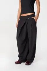 Pantalon de corte amplio y tiro alto con diseño cruzado en la cintura y cierre frontal con boton. Presenta una silueta fluida y relajada.