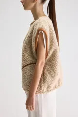 Chaleco reversible oversize de tejido tipo corderito, color beige con detalles de costuras y ribetes en marrón y cierre frontal con cremallera.