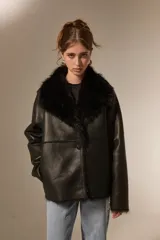 Chaqueta de eco-cuero color beige con interior y cuello de piel sintética al tono. Presenta un diseño holgado, cierre frontal con un botón y solapas amplias.