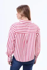 Camisa de manga larga con diseño de rayas verticales en color blanco y negro, cuenta con cuello clásico, cierre frontal de botones y un bolsillo en el pecho.