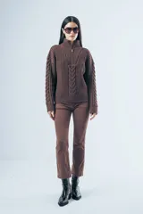 Sweater de punto color marrón, con cuello alto y cierre frontal parcial, de manga larga con diseño de trenzas en las mangas y el frente.