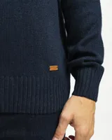 Buzo tejido de punto con cuello redondo, manga larga y puños y ruedo acanalados. Presenta un diseño clásico y versátil con un pequeño detalle de etiqueta en el lateral inferior.