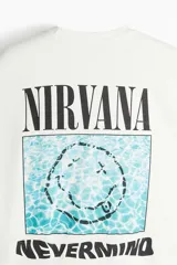 Remera de algodón color crema con cuello redondo acanalado y diseño estampado de Nirvana Nevermind en el centro del pecho.