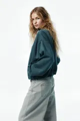 Chaqueta de punto pesado con escote redondo, cierre frontal y bolsillos laterales insertados. Diseño oversized con hombros caídos, puños y bajo elásticos.