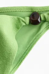 Vedetina de tiro bajo color verde, con detalle de cuentas oscuras en los laterales delanteros y costura fruncida en la parte trasera.