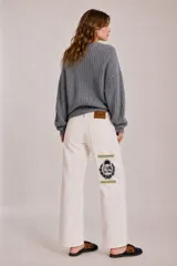 Jean de tiro bajo y corte recto, color blanco, con bolsillos y bordado del escudo nacional en la parte trasera.