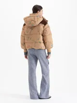 Campera puffer color tostado con estampado de figuras esquiando, capucha desmontable, recortes en corderoy marrón en los hombros, puños tejidos y cierre frontal con botones a presión.